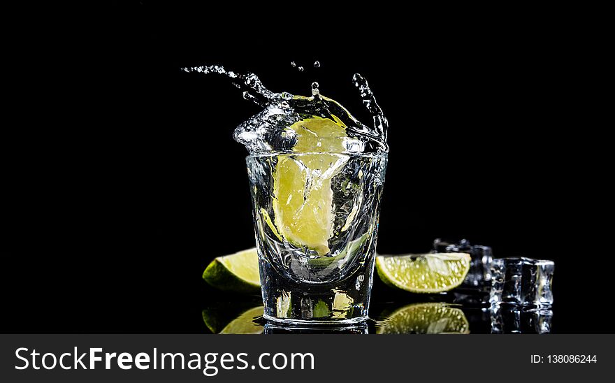 Mexican traditional Tequila splash lime on black background with ice cube. Mexican traditional Tequila splash lime on black background with ice cube