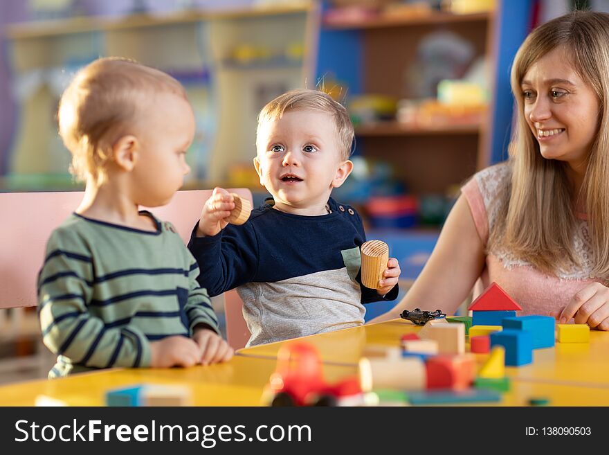 Babies playing with teacher in kindergarten or nursery