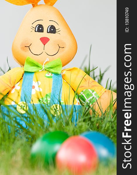 Toy easter bunny with colored eggs in the grass