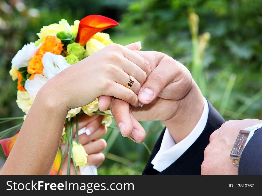Newlywed couple holding hands over bouquet of flowers. Newlywed couple holding hands over bouquet of flowers.