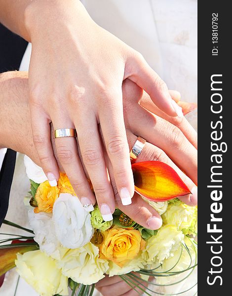 Newlywed couple holding hands over bouquet of flowers. Newlywed couple holding hands over bouquet of flowers.