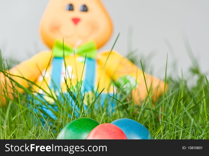 Toy easter bunny with colored eggs in the grass