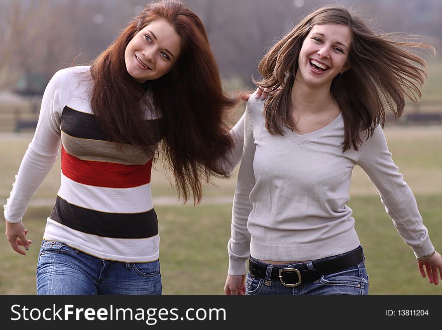 Two cheerful walking girls in the park. Two cheerful walking girls in the park