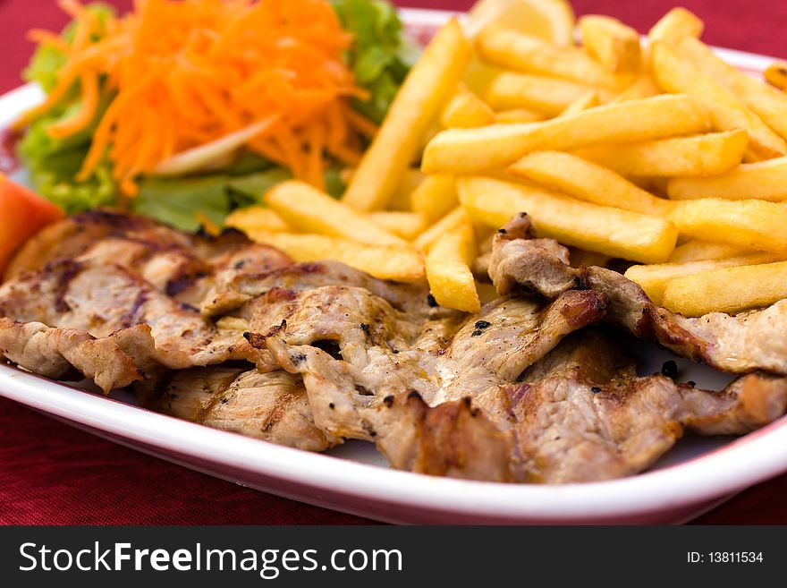 Fresh grilled Pork Chop with french fries and salad of carrot and lettuce