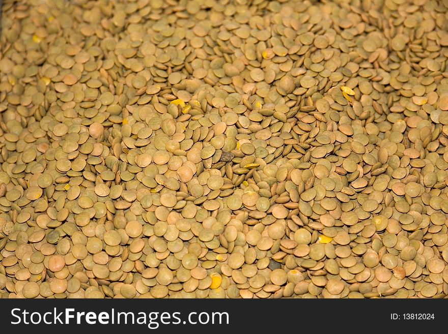 Big Heap of dried brown lentil close-up as background.