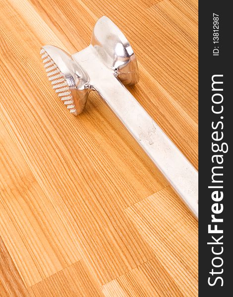 Aluminium meat tenderizer on wooden background.