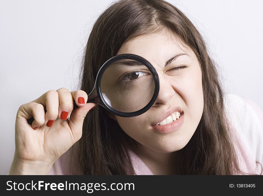 Pretty young woman looking through magnifying