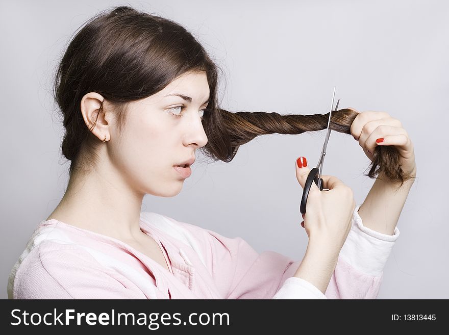 Young attractive woman is cutting her hair, over white