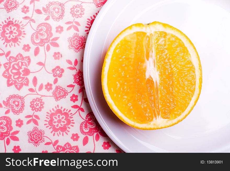 Orange on plate on napkin with flowers