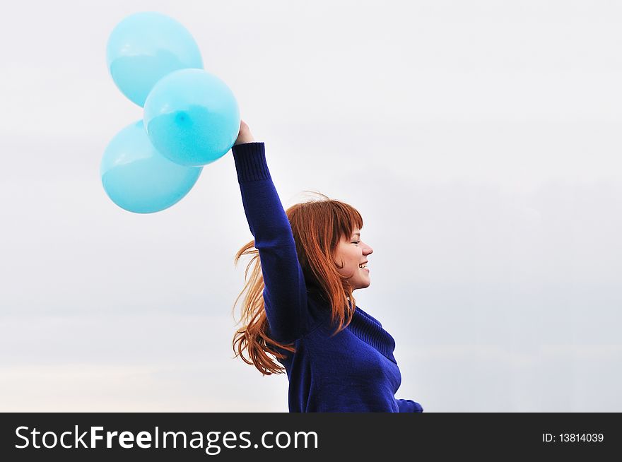 Redheaded girl running with balloons over the sky