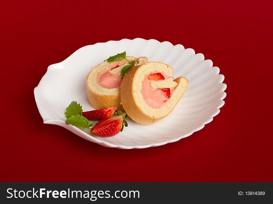 Swiss roll with strawberry cream on red background