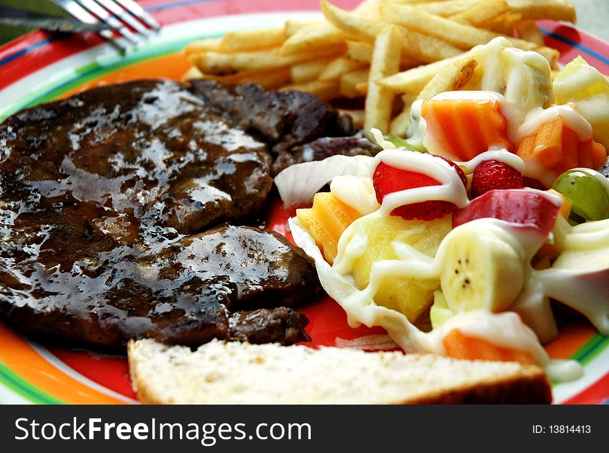 Beefsteak Served with French fries and salad.