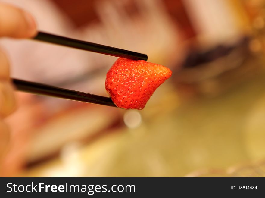 A man holding strawberry by chopsticks at chinese restaurant, Beijing. A man holding strawberry by chopsticks at chinese restaurant, Beijing