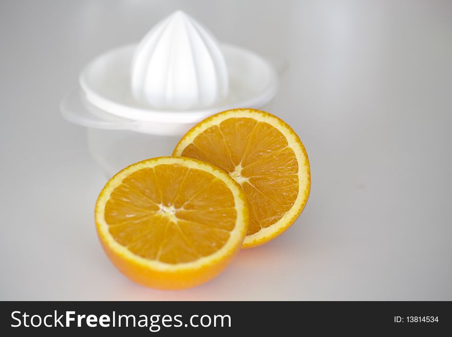 Orange fruit sliced in half with white plastic juicer at the background. Orange fruit sliced in half with white plastic juicer at the background.