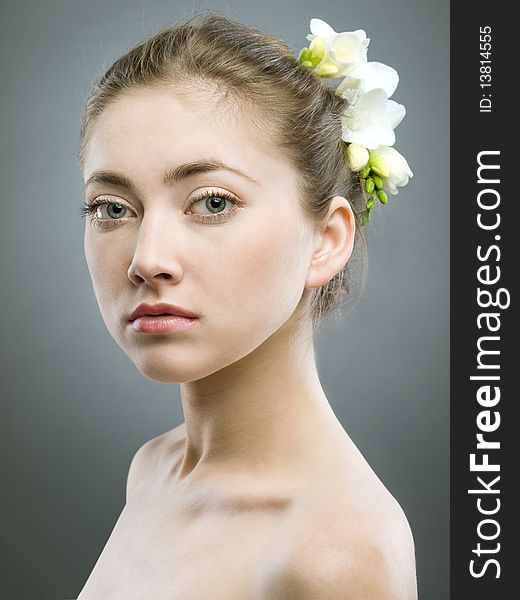 Portrait of beautiful girl with white freesia on grey background. Portrait of beautiful girl with white freesia on grey background