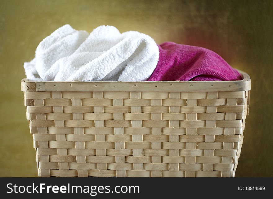 Wooden basket with white and pink towels in front of golden wall. Wooden basket with white and pink towels in front of golden wall.