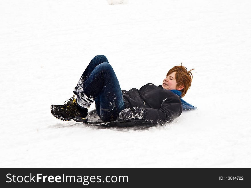 Child sledding down the hill in snow, white winter