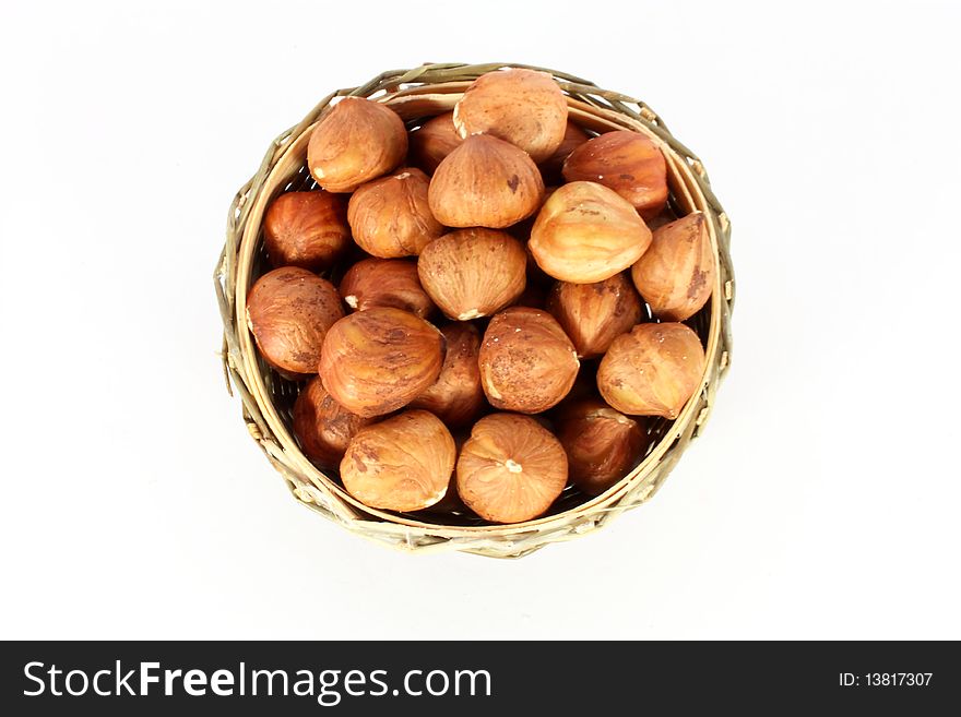Hazelnuts in a round basket, isolated on white