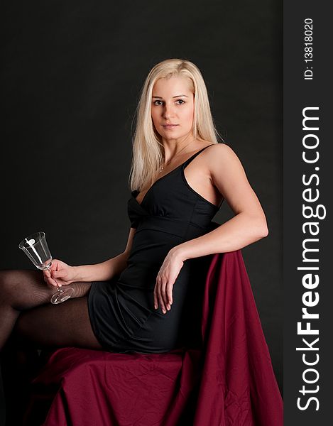 Blonde girl with a wineglass, posing in studio