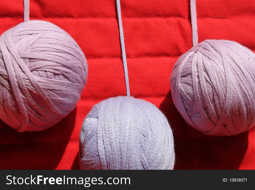 Threads, threads in the coil, skeins of thread, three large skein of knitting, knitting with natural threads, skeins of purple yarn, on a red background, leisure, lifestyles, family at home, crochet, meditative exercise