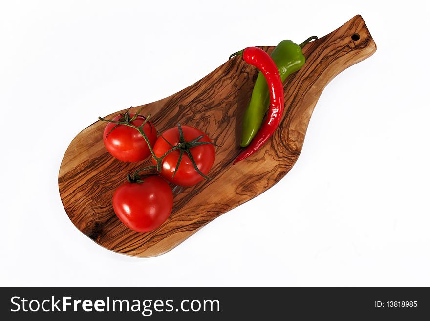 Three fresh red tomato and Chili pepper on breadboard