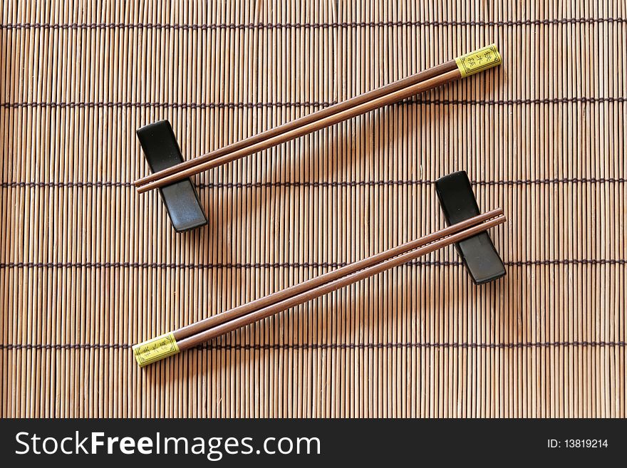 Two couples of chopsticks on a bamboo place mat