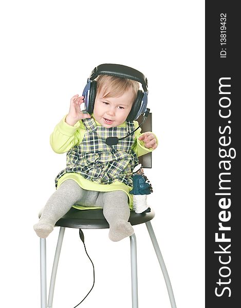 The happy small child sits on a chair in headset ear-phones with a microphone. Isolated on white background
