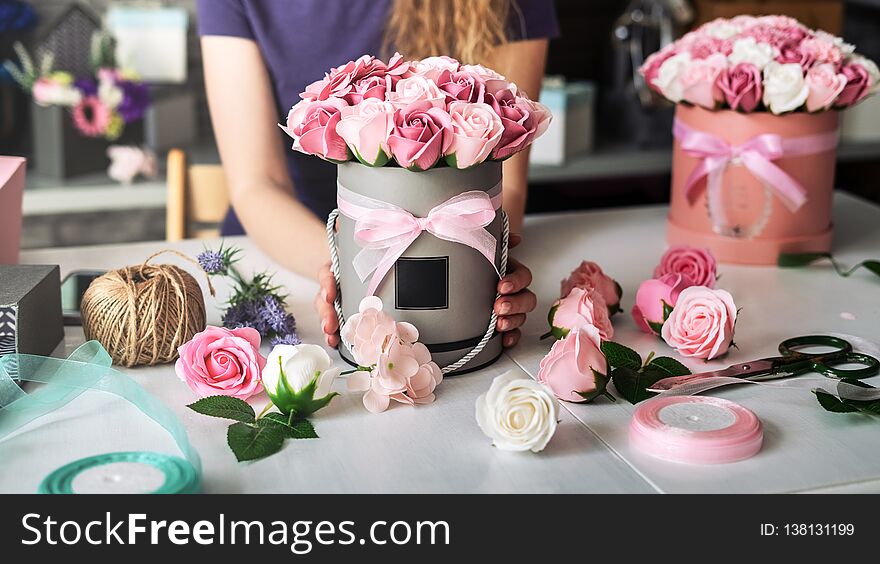 Flower Shop: A Florist Girl Collects A Bouquet In A Round Box Of Pink Roses. Blond Curly Hair, Gray Background.