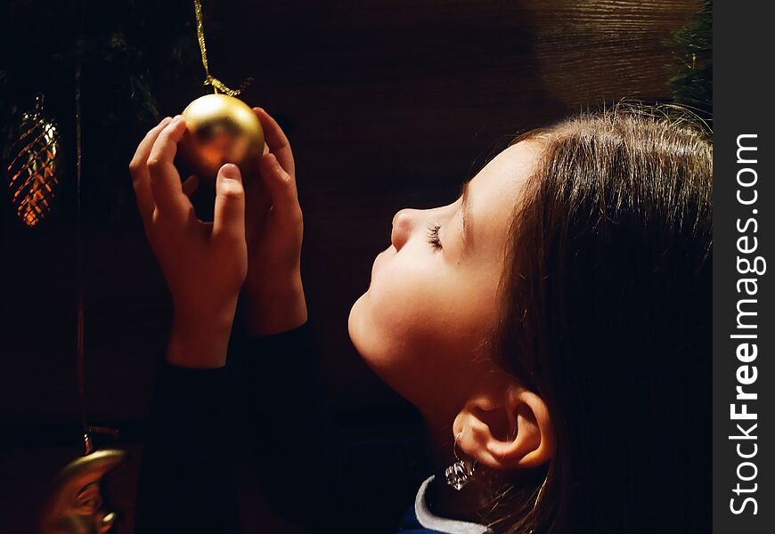 Little Girl Holding Christmas Decoration On The Christmas Tree In Her Hand