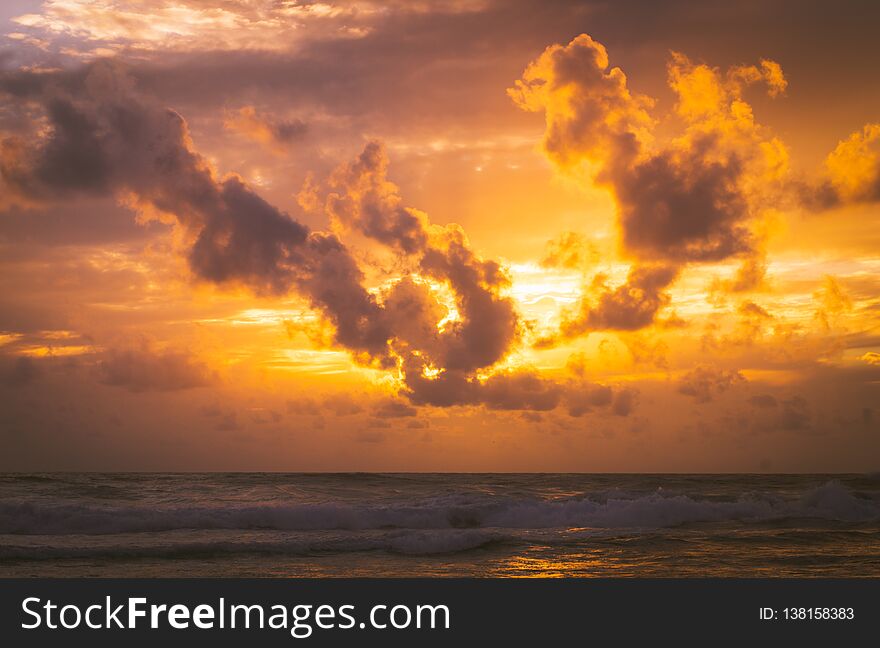 Fiery golden sunset at sea with soft clouds