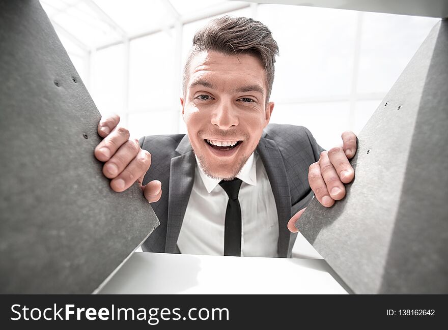 Businessman in the background smiling and holding documents that stand on a shelf in a cabinet