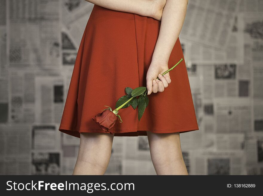 Female wearing red dress holding a rose behind her back