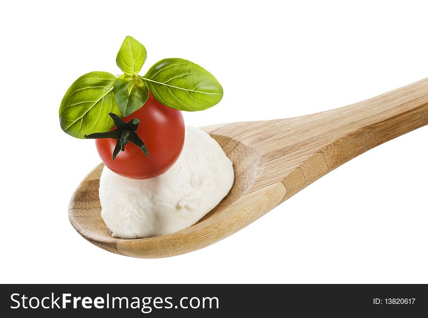 Tomato, mozzarella and basil on a wooden spoon close up. Tomato, mozzarella and basil on a wooden spoon close up