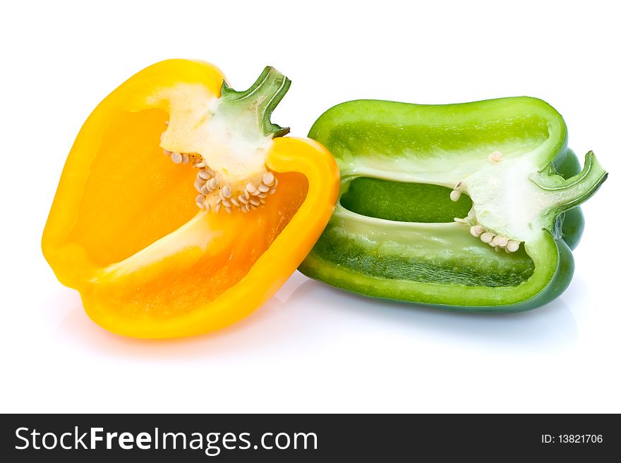 A yellow and green pepper cut in half and placed side by side on a white background. A yellow and green pepper cut in half and placed side by side on a white background