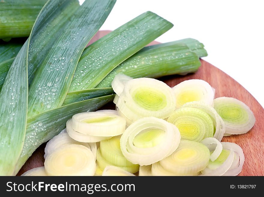 Whole and sliced fresh leeks on wooden chopping board on white background. Whole and sliced fresh leeks on wooden chopping board on white background