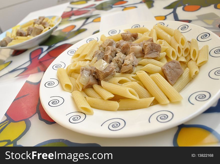 Pasta penne and pork in a plate on the kitchen table