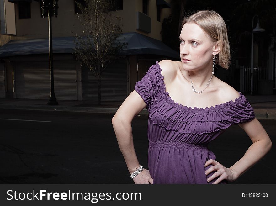 Attractive woman posing in a purple dress with her hands on her hips. Attractive woman posing in a purple dress with her hands on her hips