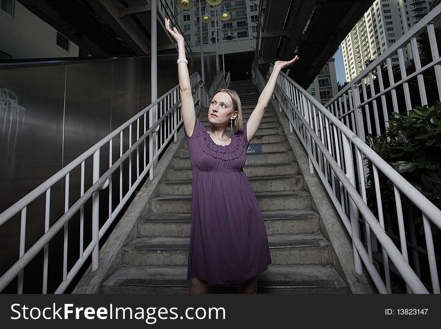 Attractive young woman posing in the city with arms extended outward. Attractive young woman posing in the city with arms extended outward