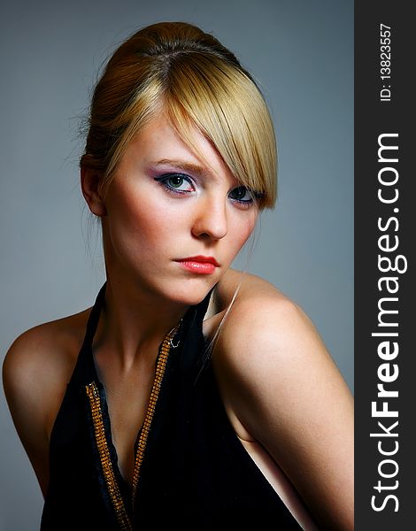 Young woman posing on grey background in black dress. Young woman posing on grey background in black dress