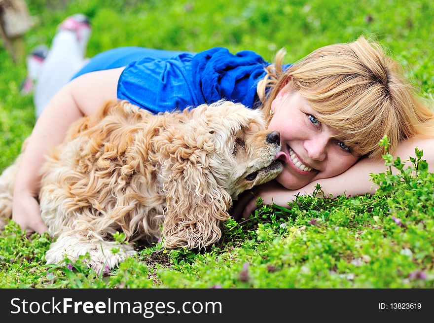 Woman and dog laying on the meadow, dog licking woman's cheek. Woman and dog laying on the meadow, dog licking woman's cheek