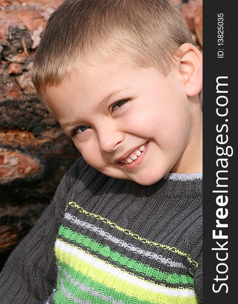 Little boy against a tree trunk on a sunny day. Little boy against a tree trunk on a sunny day