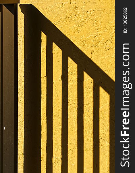 Shadow of hand rail on the yellow textured wall. Abstract. Shadow of hand rail on the yellow textured wall. Abstract.
