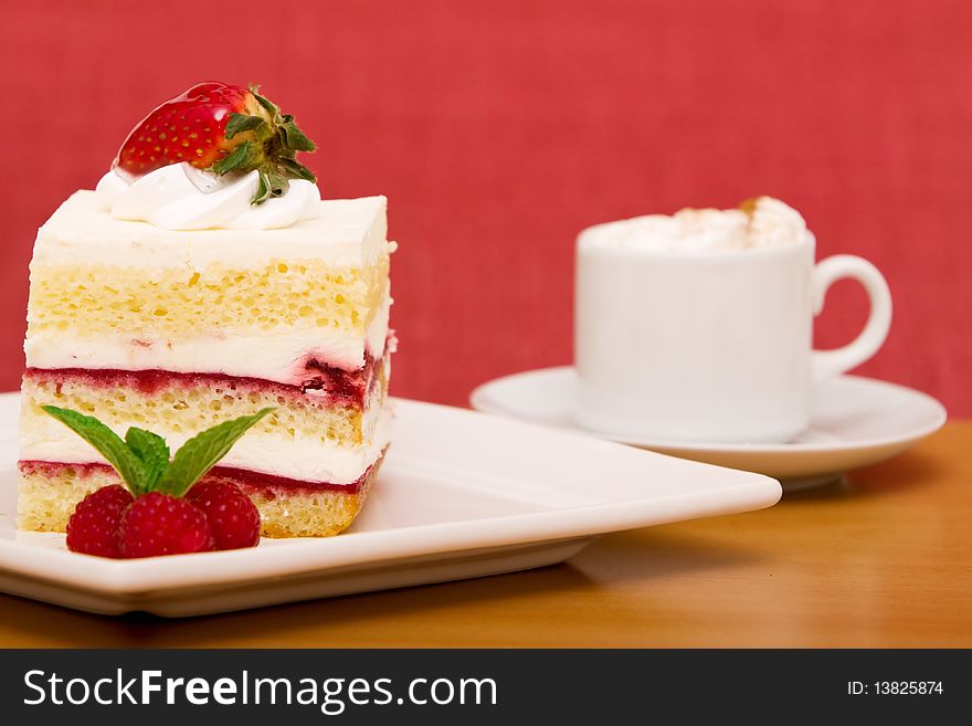 Slice of strawberry cake with cappuccino