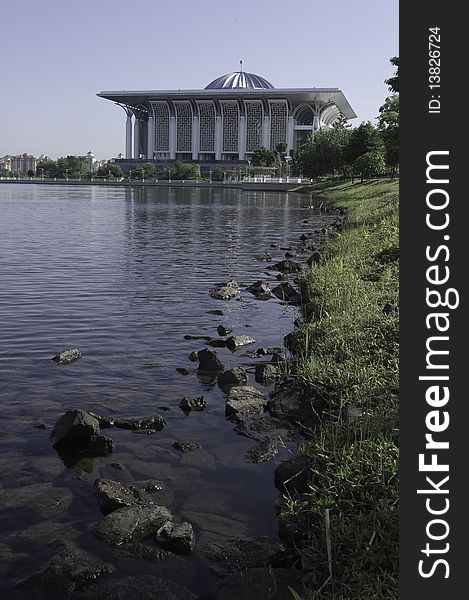 Serene scenery of rocks along lakeside of Putrajaya, Malaysia with Steel Mosque in the background