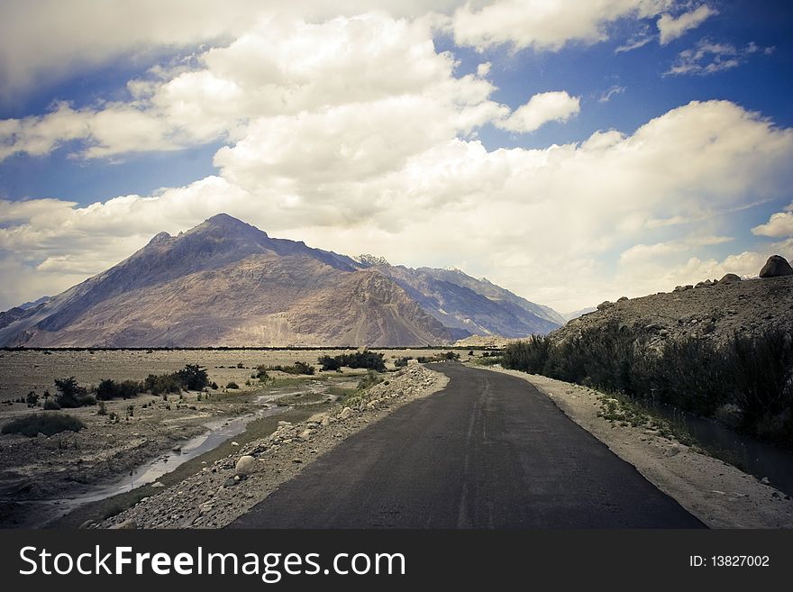 Road in Nubra valley, Ladakh, Kashmir. Mountain range and blue sky on background.
