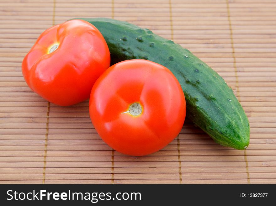 Red tomato and green cucumber on brown bamboo napkin