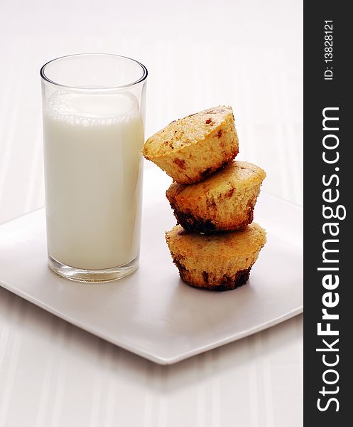 Fresh muffins with milk on white background