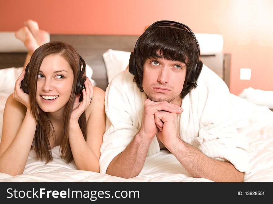 Boy and girl in headphones on bed