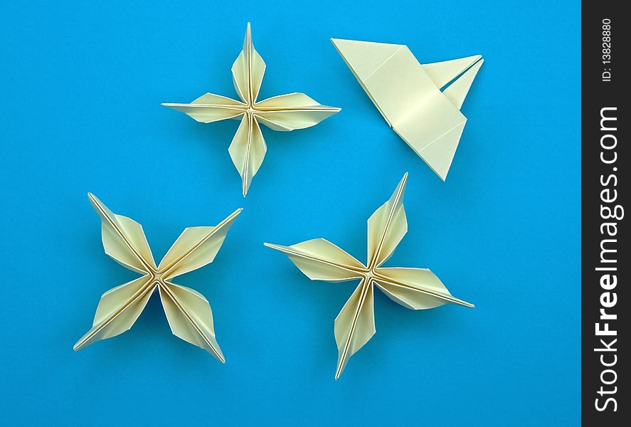 Three origami flowers with a butterfly on a blue background