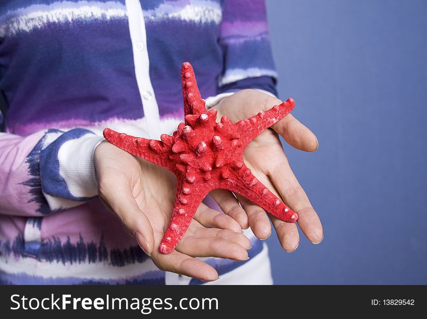 The girl in the room of her hand holding a red starfish. The girl in the room of her hand holding a red starfish